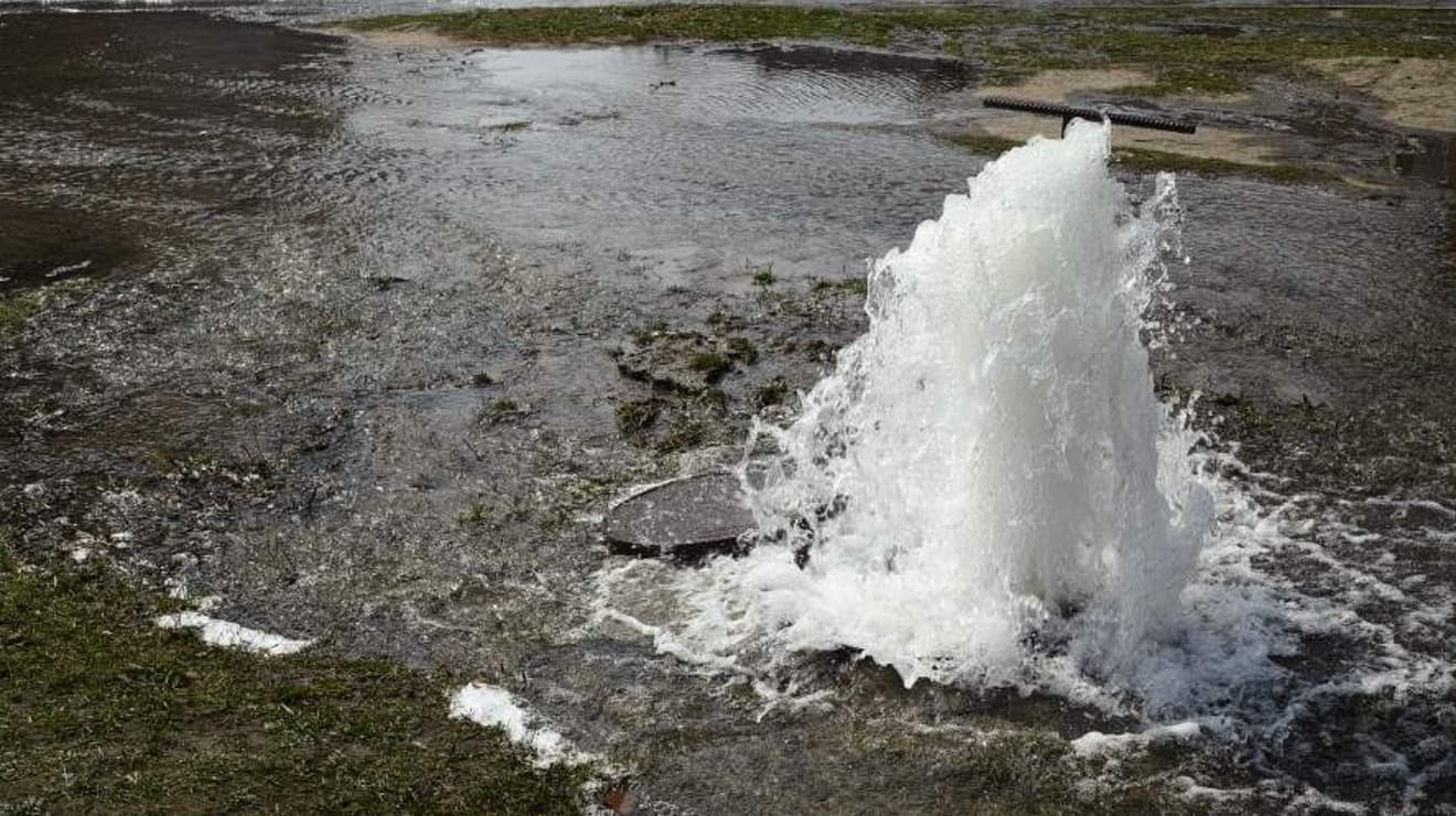 Water bubbling up onto a road from a burst water main underground