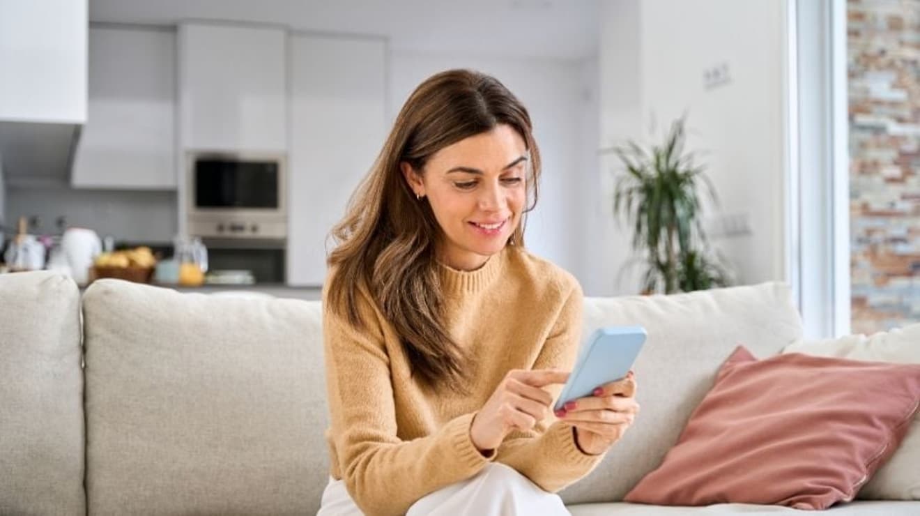 woman at home on the sofa looking at the customer services hub on her phone