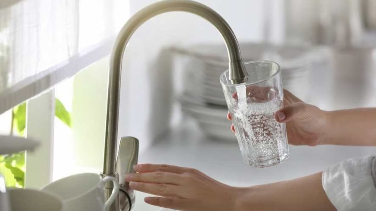 Woman using the tap to pour a glass of tap water