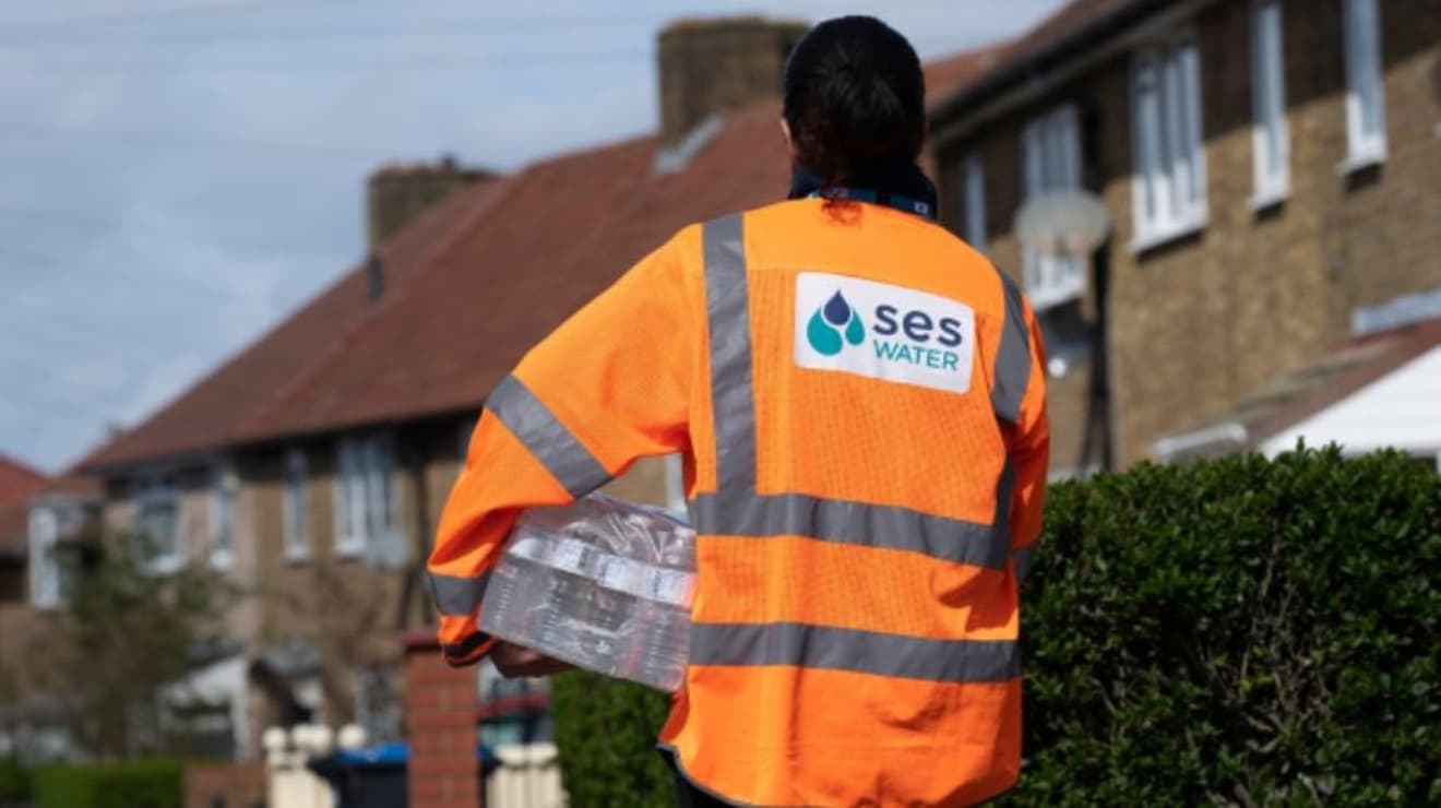 SES member of staff in the street delivering bottled water to homes