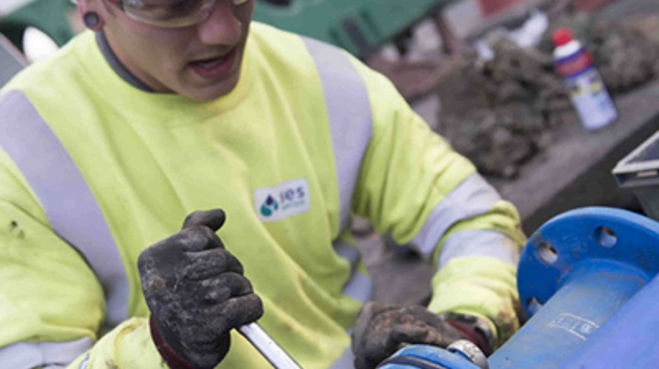 Man fixing a blue pipe with a spanner
