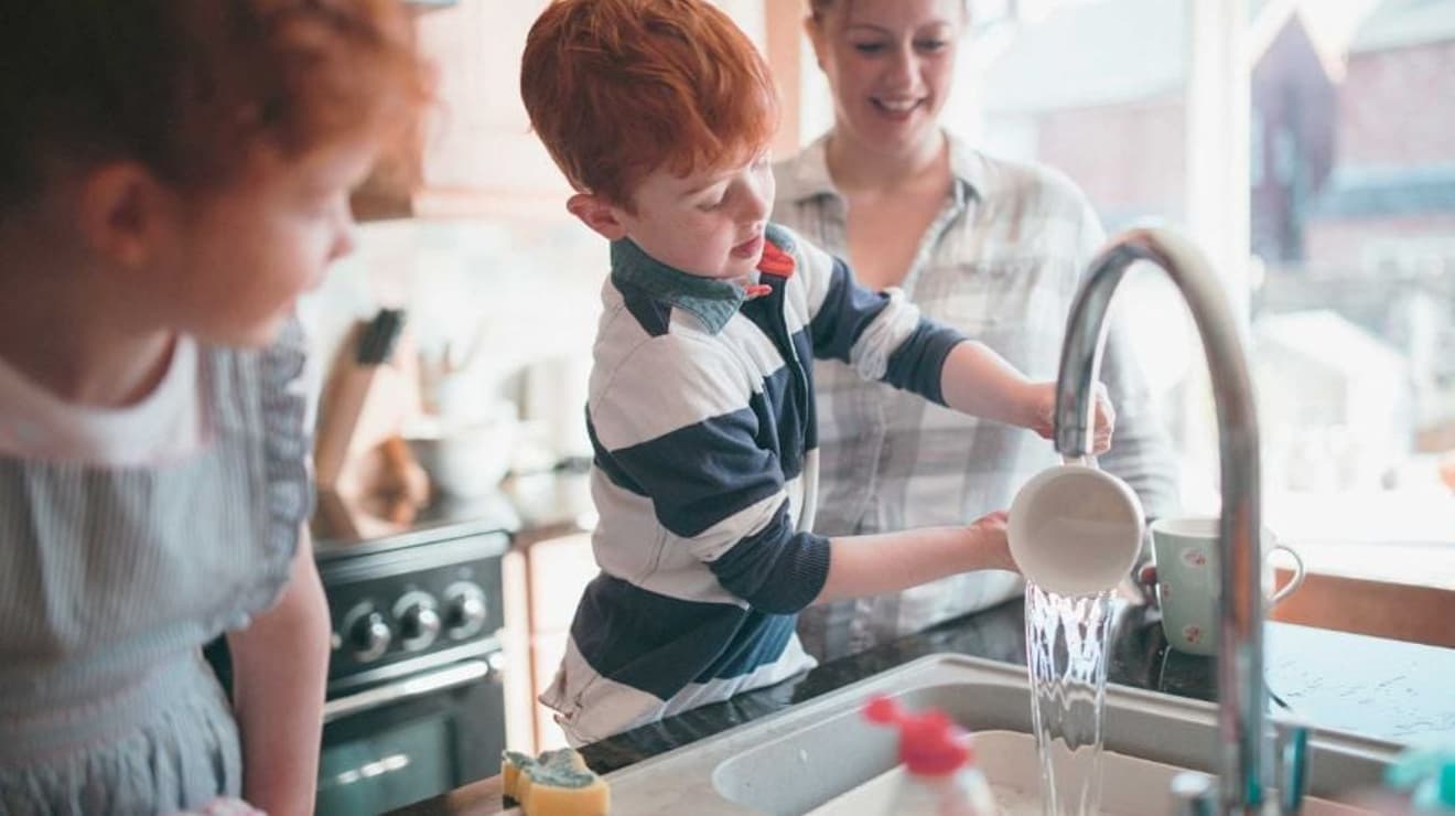 Two children and a mother in the kitchen washing up together