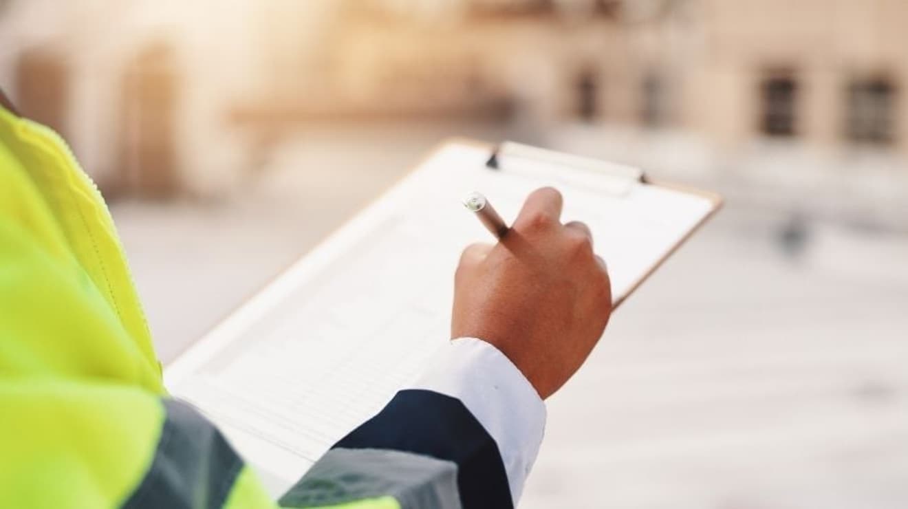 Inspector writing on a clipboard on site with a blurred background