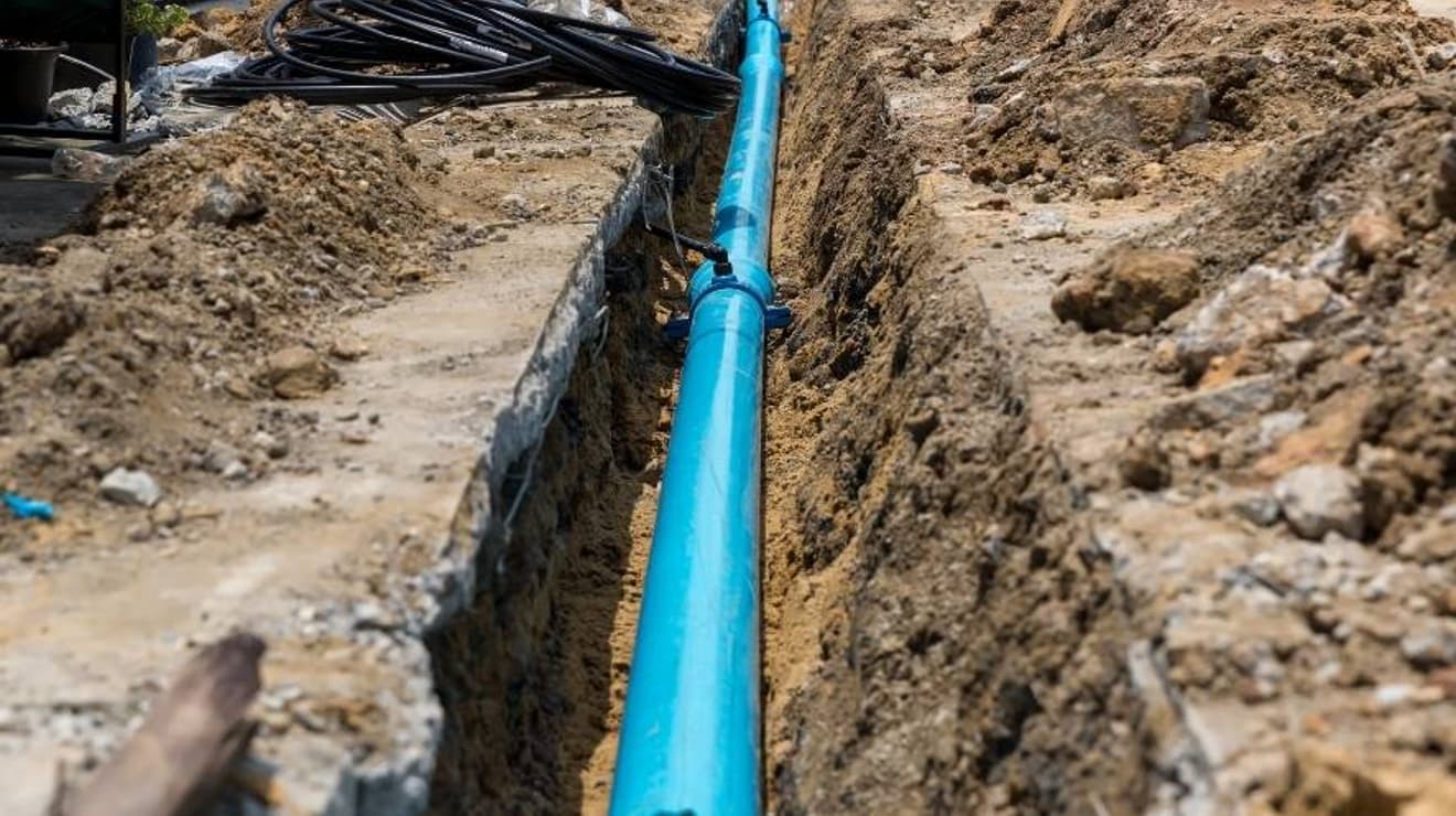 water main pipe being installed into dug out trench