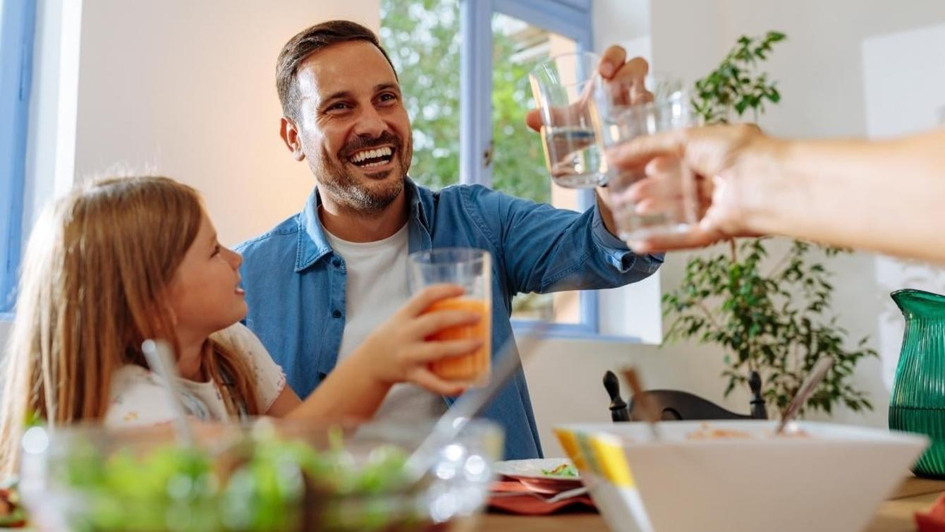 Man with daughter drinking water at the dining table
