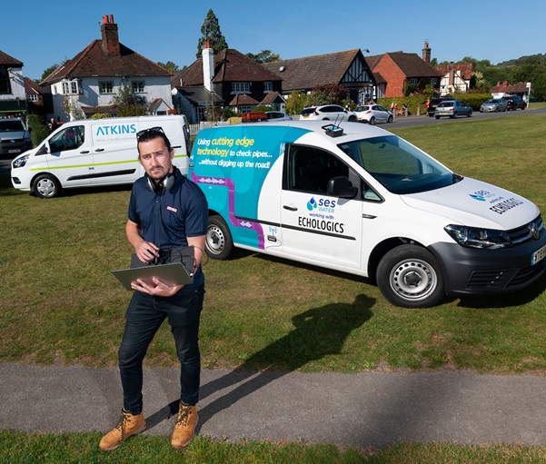 Man holding a laptop stood in front of to work vans